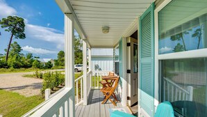 A covered porch with a wooden table and chairs, a view of the surrounding landscape, and a building with green shutters. - 2 Mi to Carrabelle Beach: Home w/ Yard & Porch (Carrabelle)