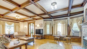 Amplia sala de estar con piso de madera, un tapete redondo grande, un sofá, una mesa de centro y un televisor.