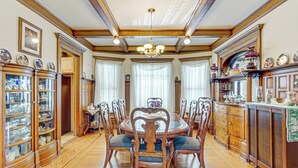 Comedor con mesa y sillas de madera, rodeado de armarios y una lámpara de araña.