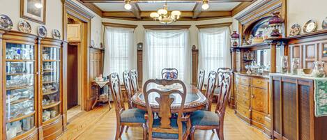 A dining room with a wooden table and chairs, surrounded by cabinets and a chandelier.