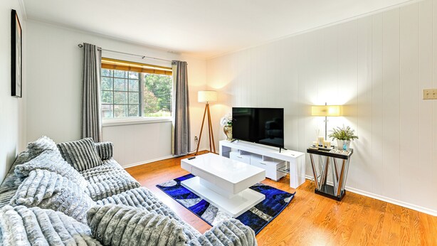 A modern living room with a white sofa, a coffee table, a TV, and a lamp. - 2 Mi to Historic Dtwn Nacogdoches: Cozy Apartment! (Nacogdoches)