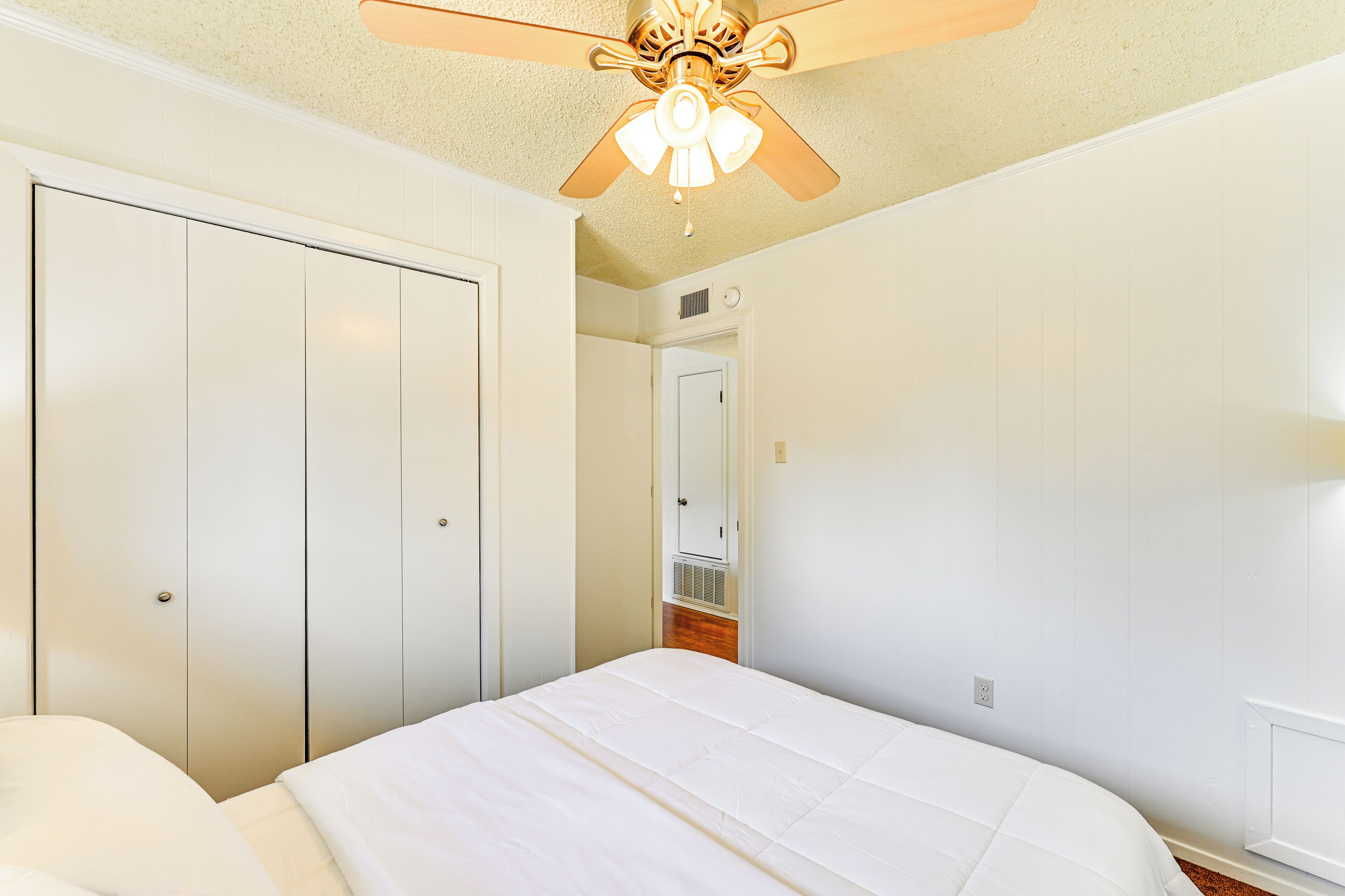 A bedroom with a bed, a ceiling fan, and a wardrobe.