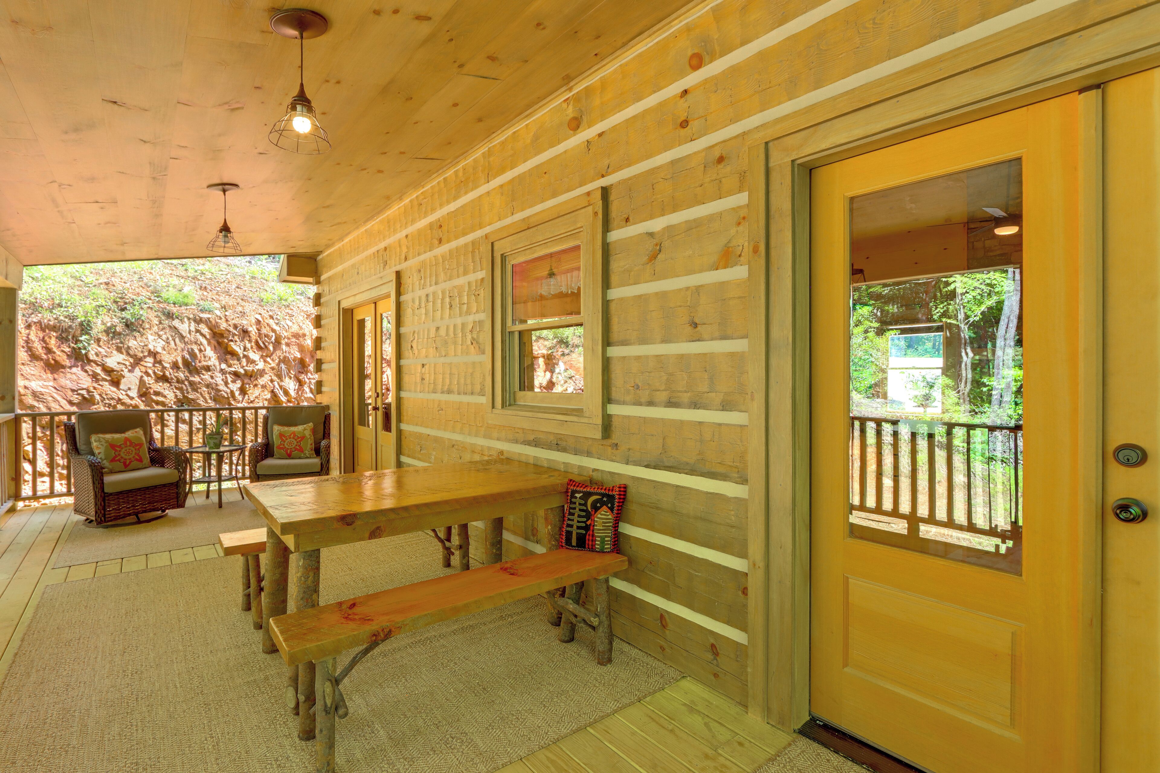 A wooden interior with a wooden bench, a table, and two chairs with cushions.