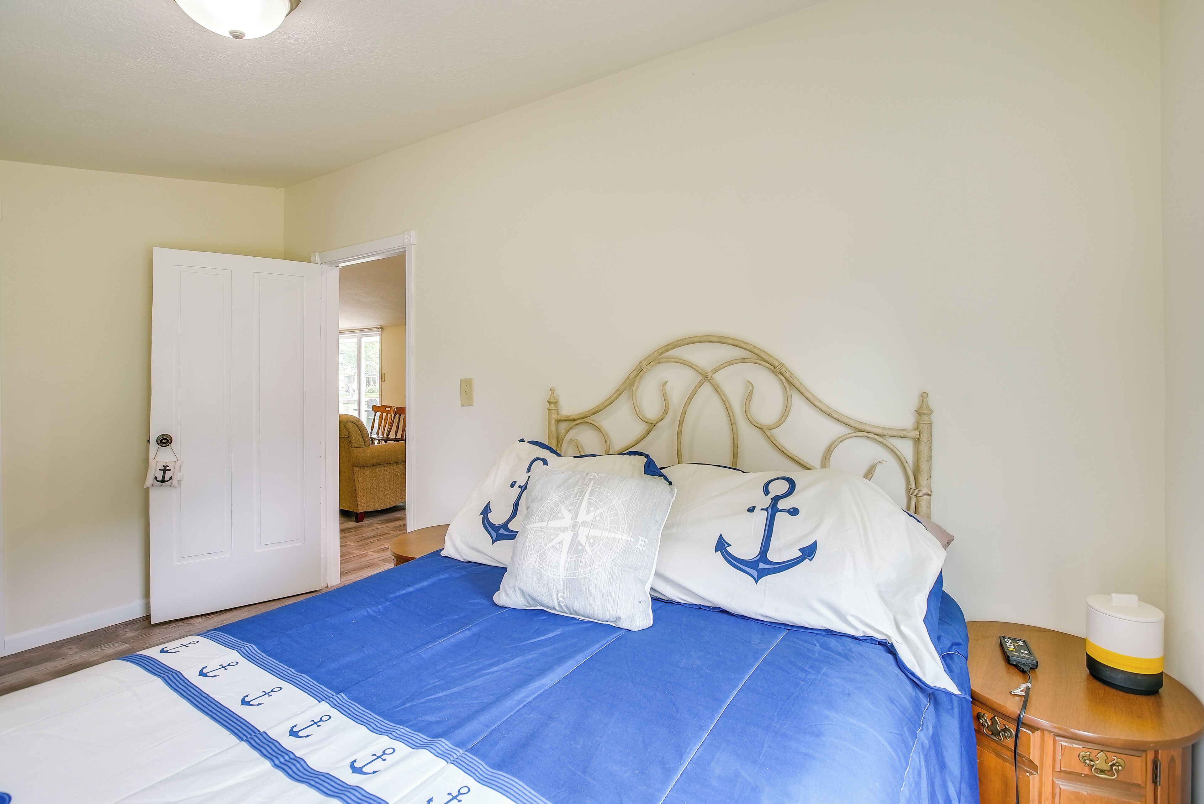 Un dormitorio con cama, mesita de noche y puerta que da a otra habitación.