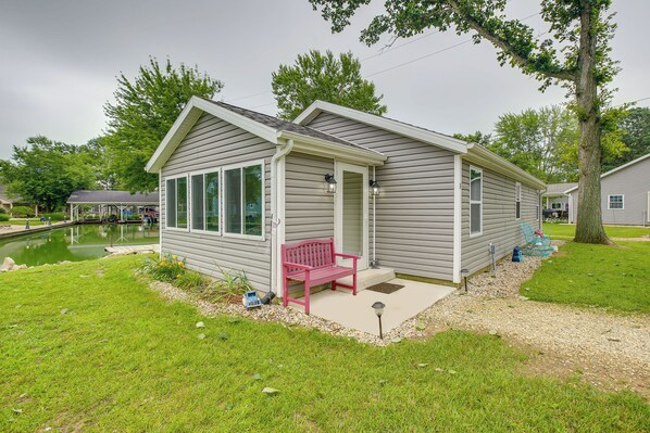 Een gelijkvloers huis met een overdekte veranda, een vijver en een rode bank.