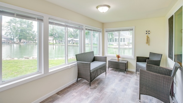 A room with large windows overlooking a body of water, wicker furniture, and a ceiling light fixture.