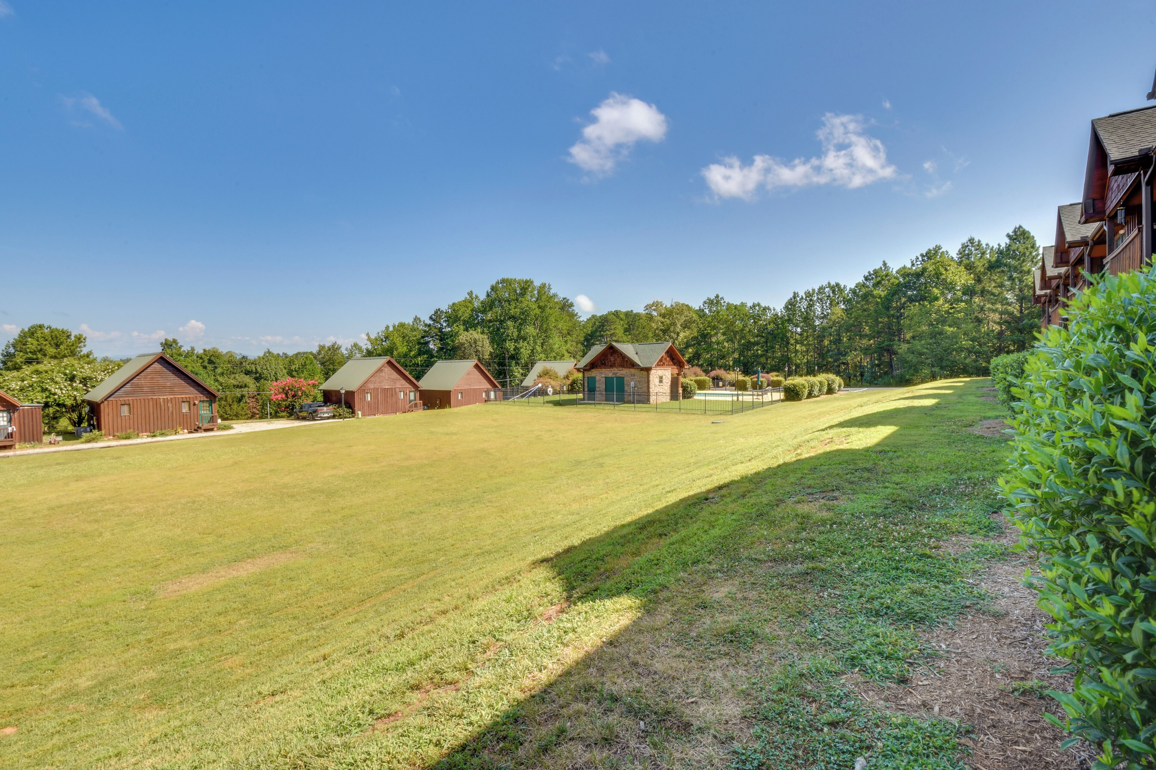 A large grassy field with several wooden buildings, likely cabins or cottages, in a rural setting.