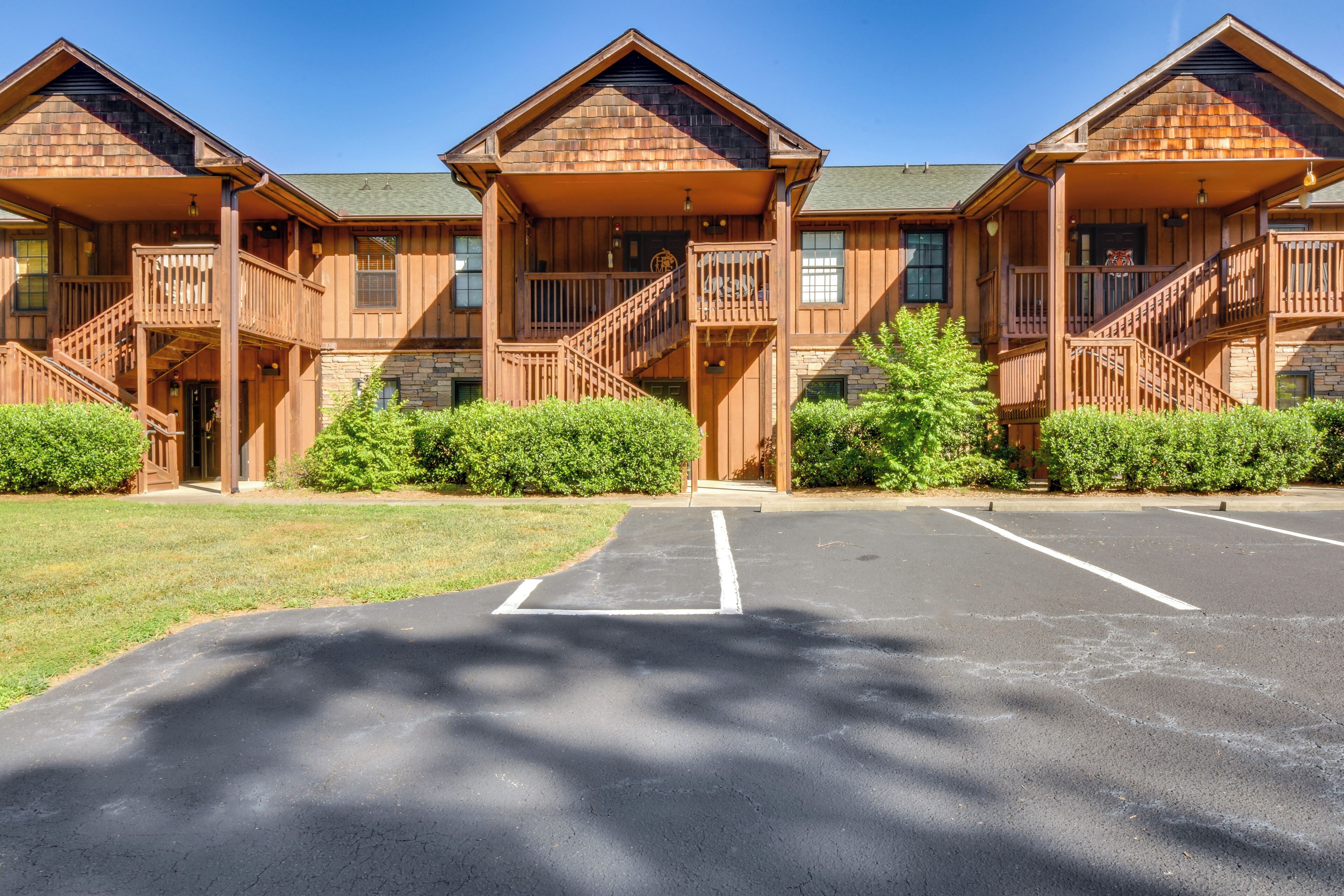A row of log cabin-style buildings with multiple balconies and a parking lot in front.