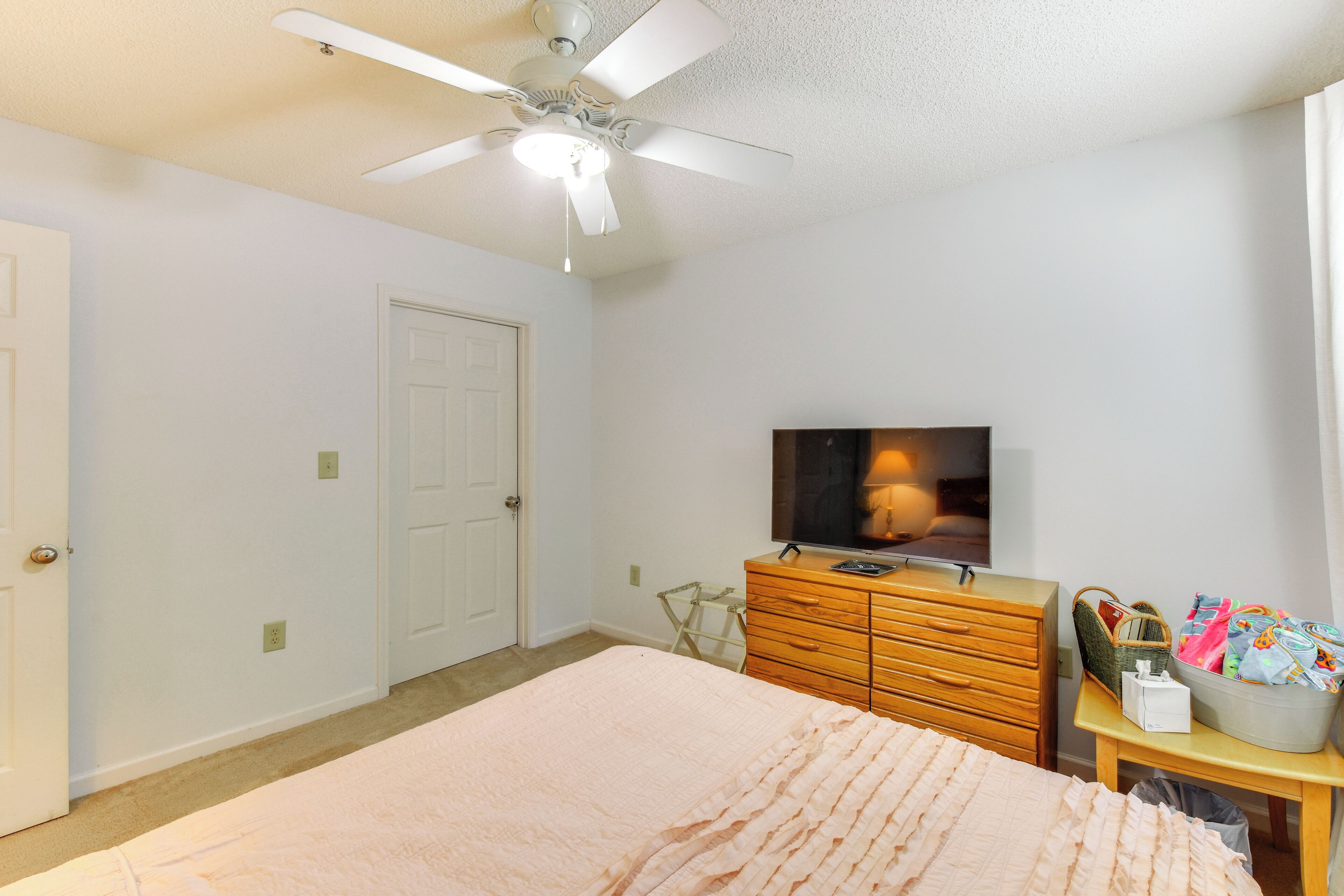 Une chambre à coucher comprenant un lit, une commode, un téléviseur et un ventilateur de plafond.