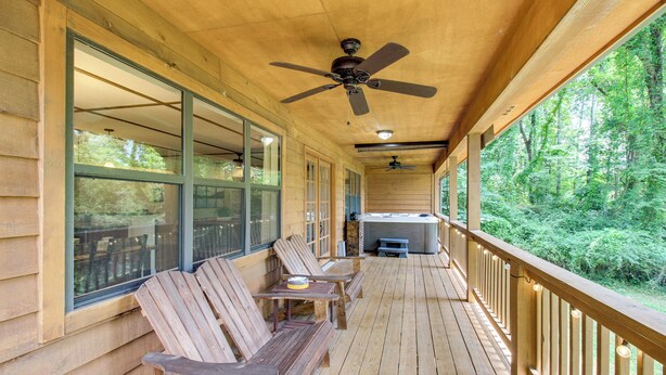 A wooden deck with outdoor seating, a hot tub, and a view of a forest. - Dock & Hot Tub: Tennessee River Cabin Getaway (Whitwell)