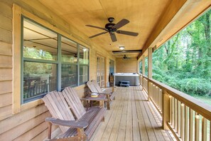 Eine Holzterrasse mit Sitzgelegenheiten im Freien, einem Whirlpool und Blick auf einen Wald.