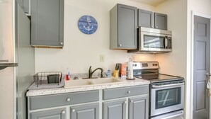 A kitchen with grey cabinets, a stainless steel microwave, an oven, and a sink with a marble countertop. - Boat Dock: Couple's Grand Lake Getaway! (St. Marys)