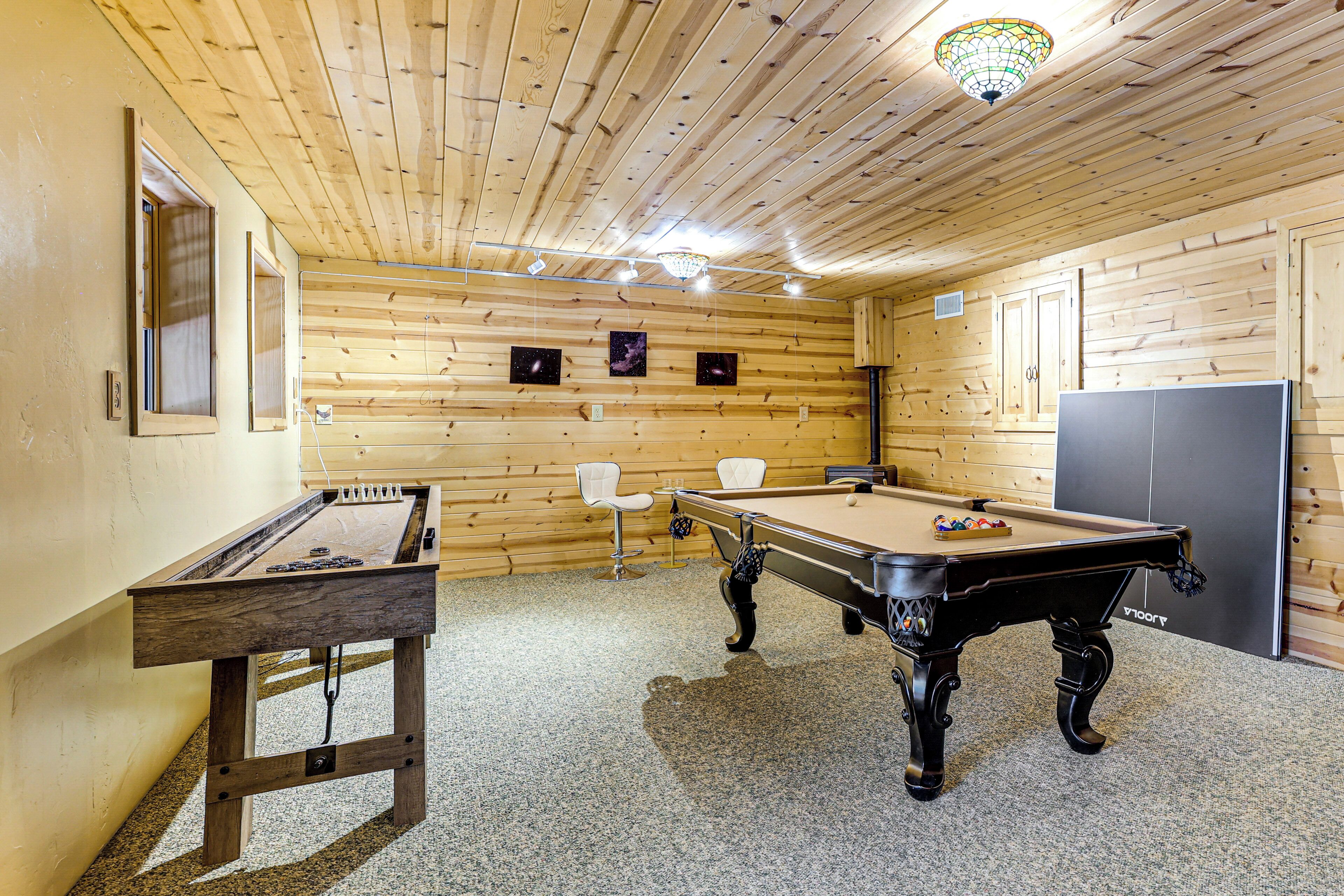 A wooden-floored room with a pool table, a foosball table, and a billiards table.