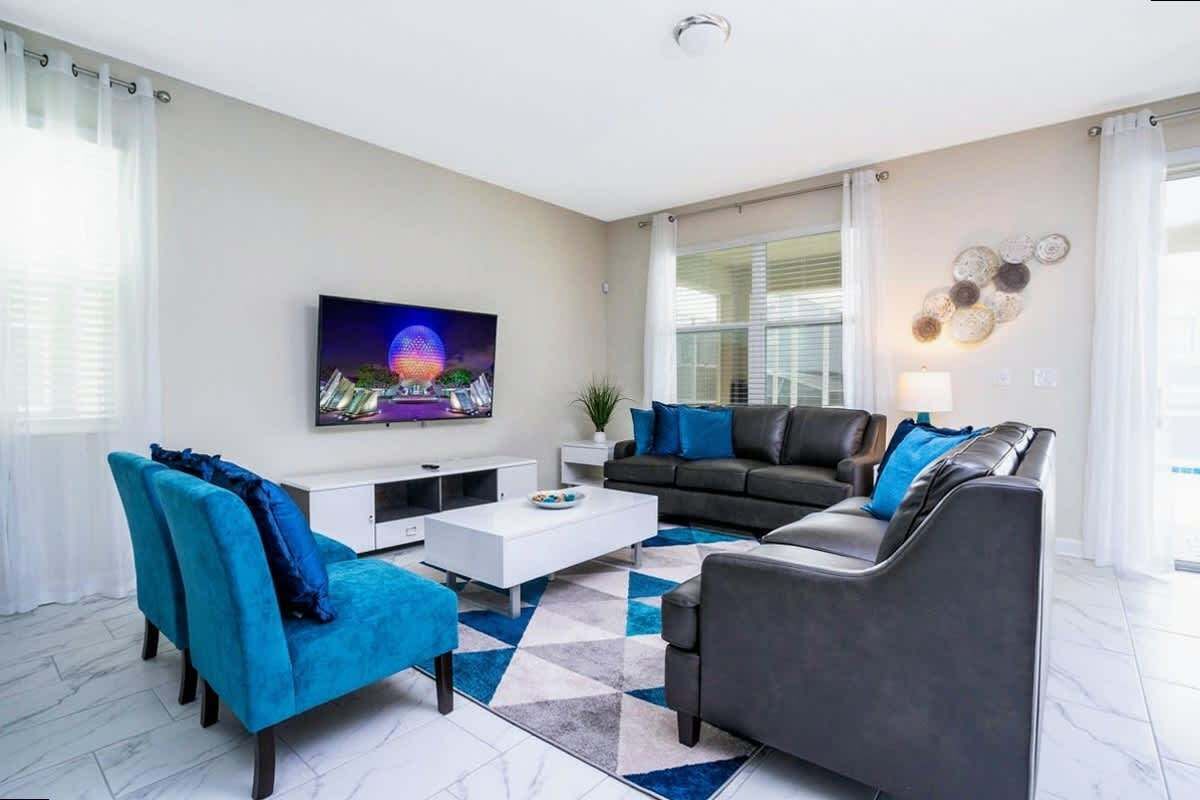 Un salon moderne avec un téléviseur à écran plat, un canapé, une table basse et un tapis à motifs.