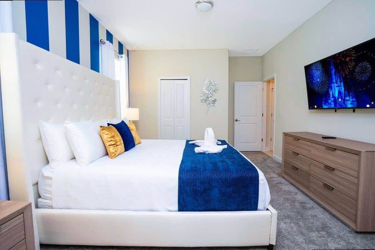 A hotel room with a large bed, a TV mounted on the wall, and a dresser.