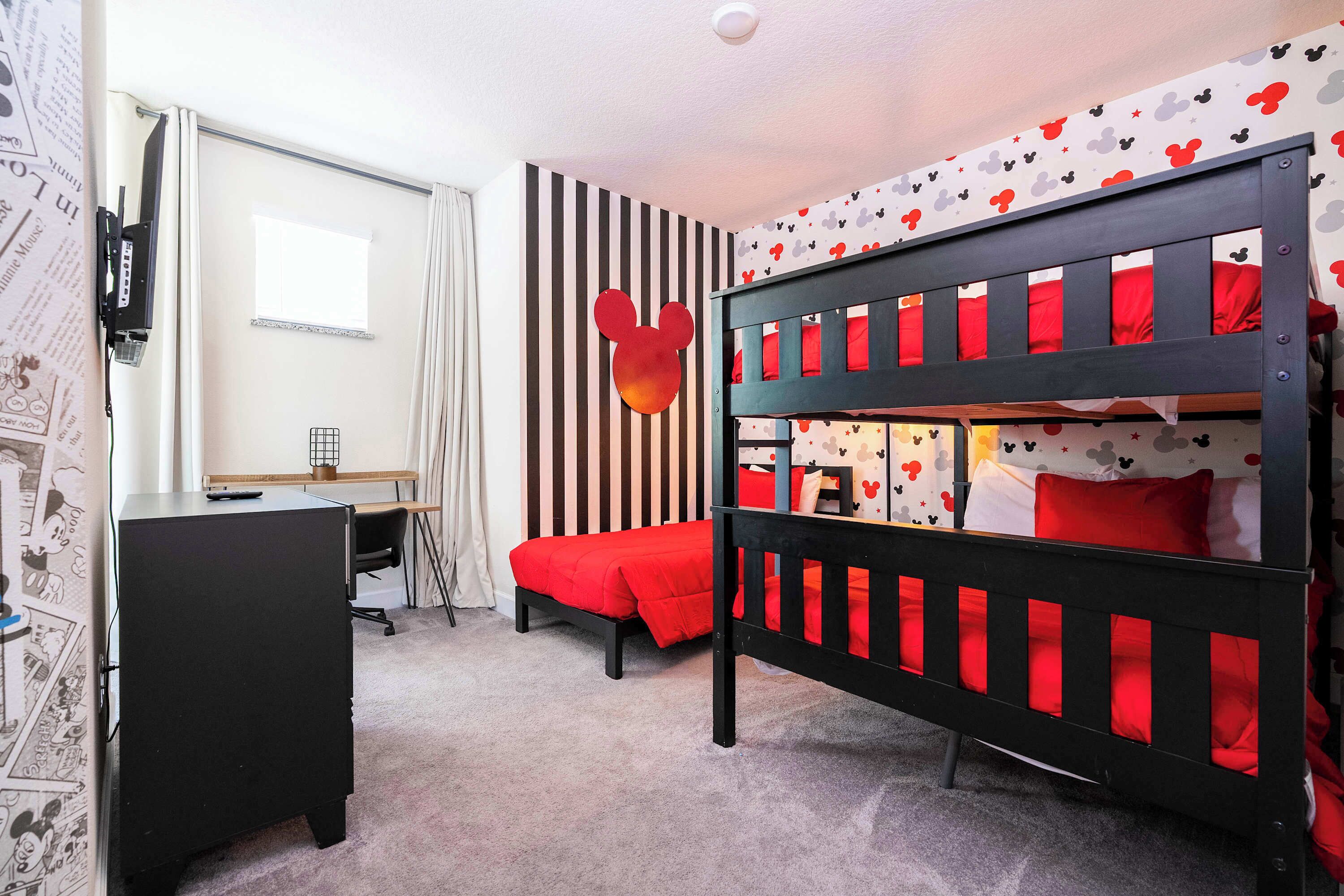 A room with a bunk bed, a desk, and a chair.