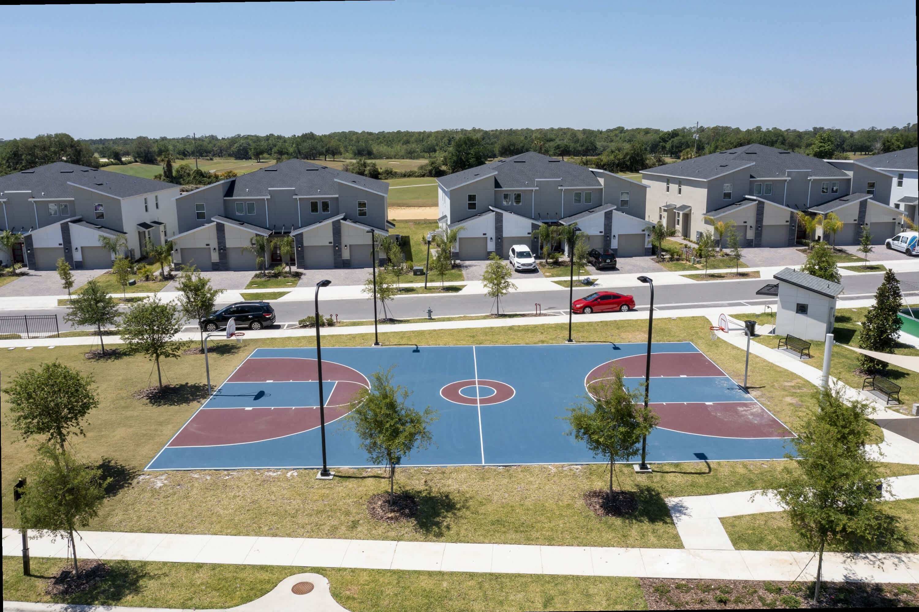 Un ensemble résidentiel comprenant des maisons modernes, un terrain de basketball et un espace de stationnement.