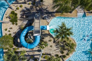 An aerial view of a pool area with a water slide, a small bridge, and palm trees. - Themed 5Bd Family Villa w Pool Spa Near Disney (Kissimmee)