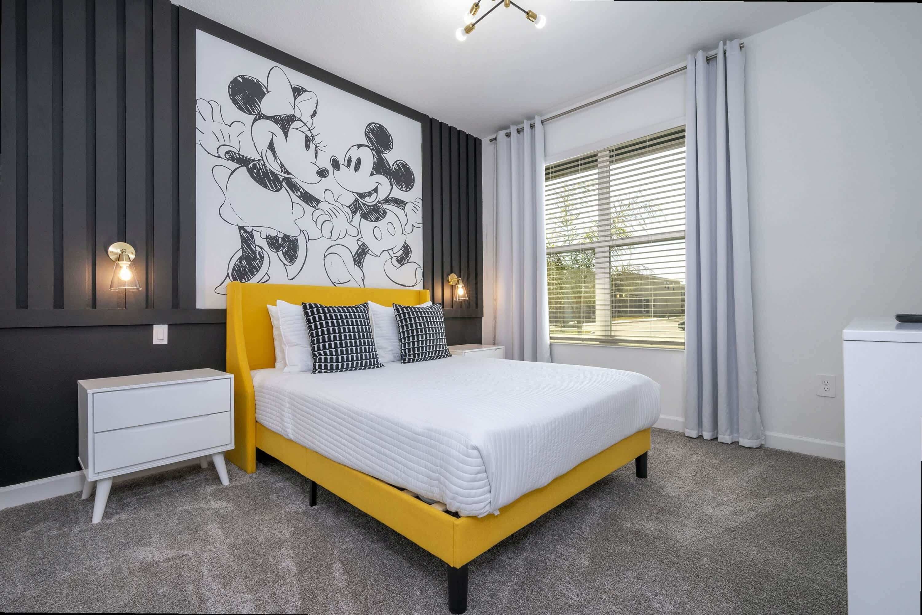 Un dormitorio moderno con cama amarilla, ropa de cama blanca, un mural grande en la pared y una ventana con persianas.