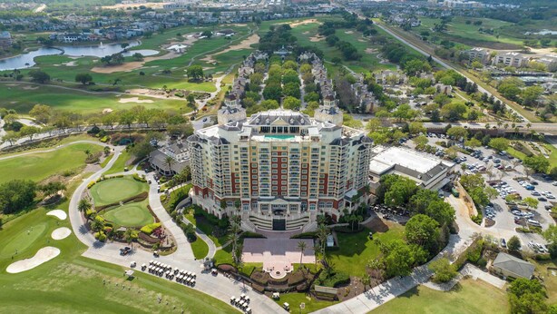 Een groot, meerlaags hotel met een centrale binnenplaats, omringd door goed onderhouden gazons en een golfbaan.