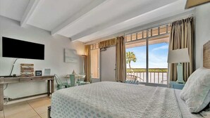 Ein Hotelzimmer mit Bett, Schreibtisch, Stuhl, Fernseher und einem Balkon mit Blick.