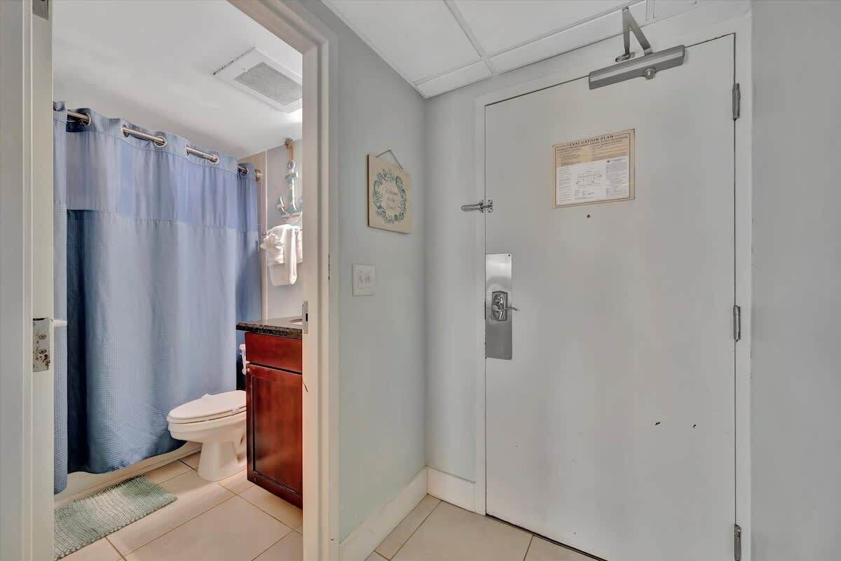 Un bagno con il water, una tenda della doccia e un armadietto.