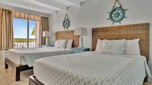 Ein Hotelzimmer mit zwei Betten, einem Balkon mit Vorhängen und einer maritimen Wandgestaltung.