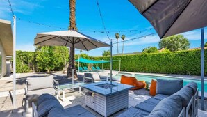 Eine Terrasse im Freien mit Pool, Sitzgelegenheiten und Sonnenschirmen.