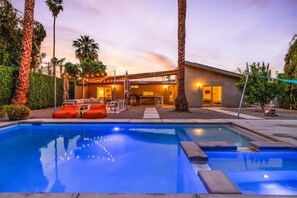 A modern house with a swimming pool, outdoor seating, and a well-lit patio area. - Modern Paradise at Sonora (Palm Desert)