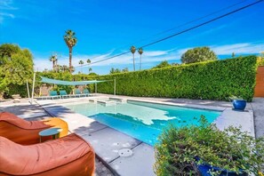 A swimming pool with lounge chairs and a covered seating area. - Modern Paradise at Sonora (Palm Desert)