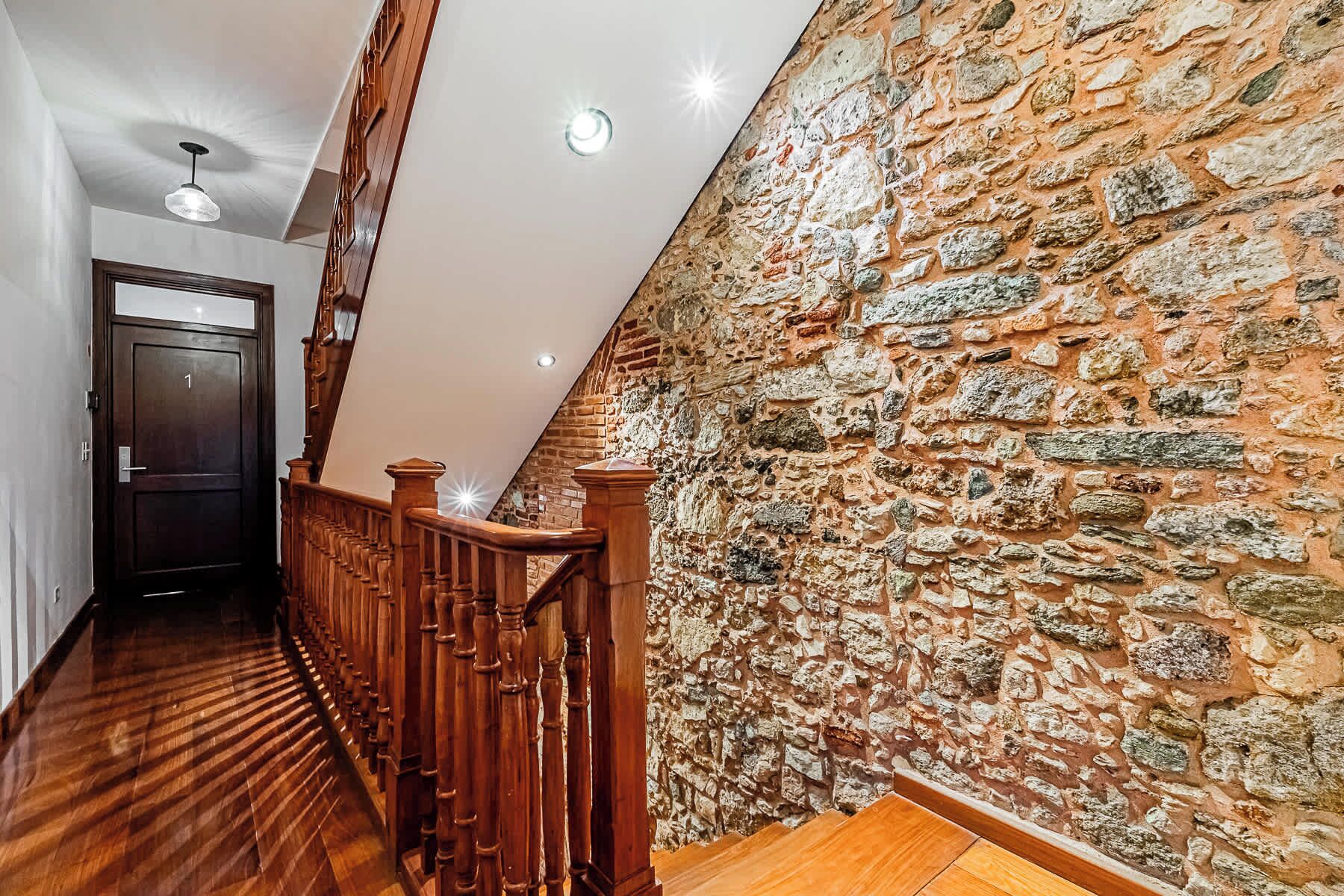 A wooden staircase with a stone wall on one side and a door at the top.