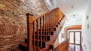A staircase with wooden balusters leading to a landing, flanked by stone walls and a polished wooden floor. - w Grandiose 1BR w Balcony in San Felipe (Panama City)
