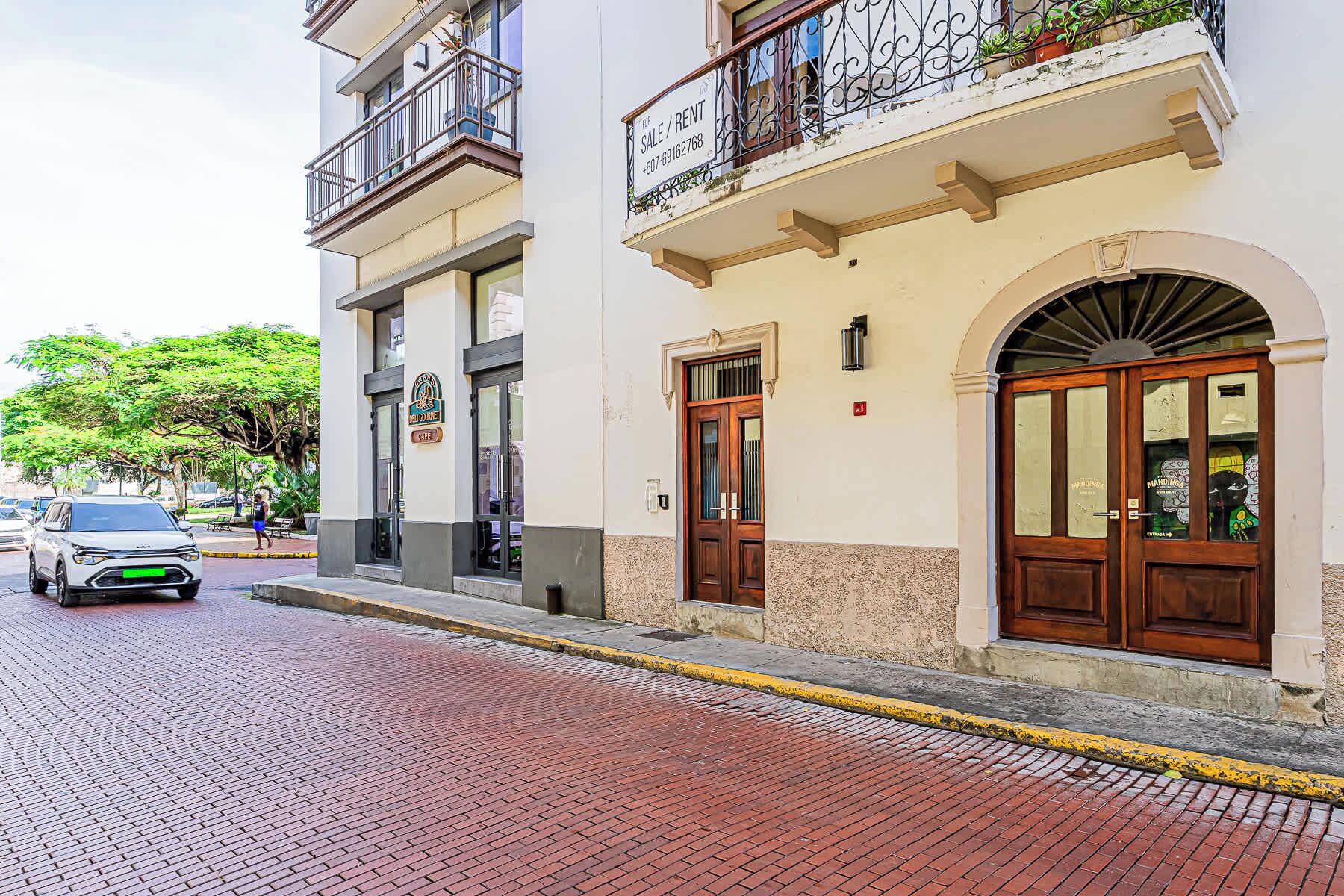 A building with a cafe sign, a wooden door, and a balcony with a wrought iron railing.