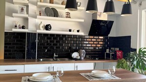 A modern kitchen with a wooden countertop, black and white shelving, and black pendant lights. - Panoramic Seaview Blue Nest - Stylish Getaway (Amfilochia)
