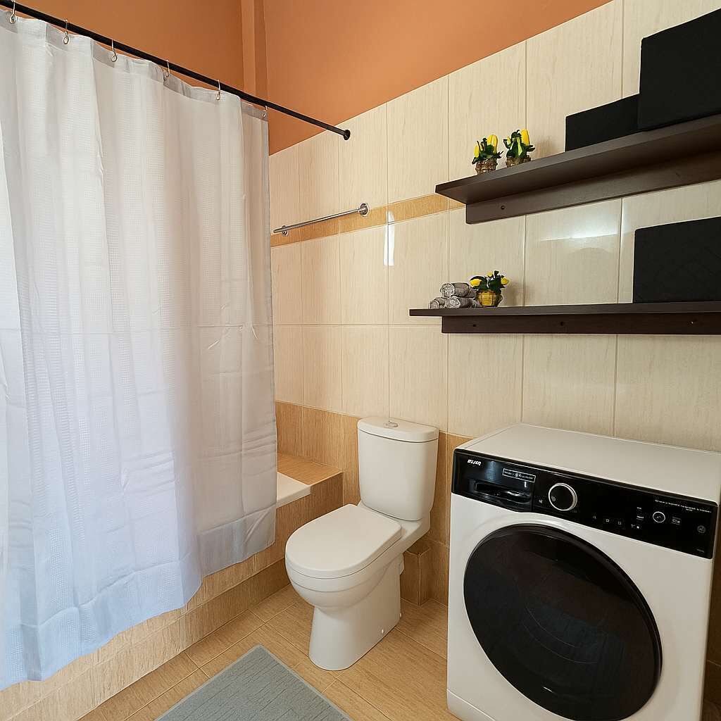 Une petite salle de bain comprenant des toilettes, un lave-linge et un rideau de douche.