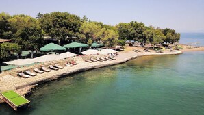 A beachside resort with sun loungers, umbrellas, and a wooden walkway along the water. - Panoramic Seaview Blue Nest - Stylish Getaway (Amfilochia)