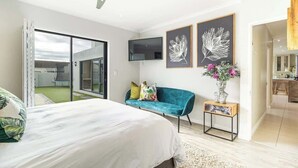 A modern bedroom with a bed, a teal sofa, a TV, and artwork on the wall. - Spacious Sunningdale Retreat With Poolside Charm (Cape Town)