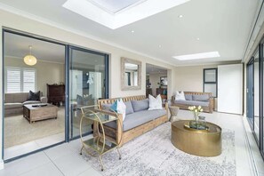 A modern living room with a glass sliding door, a sofa, a coffee table, and a ceiling skylight.