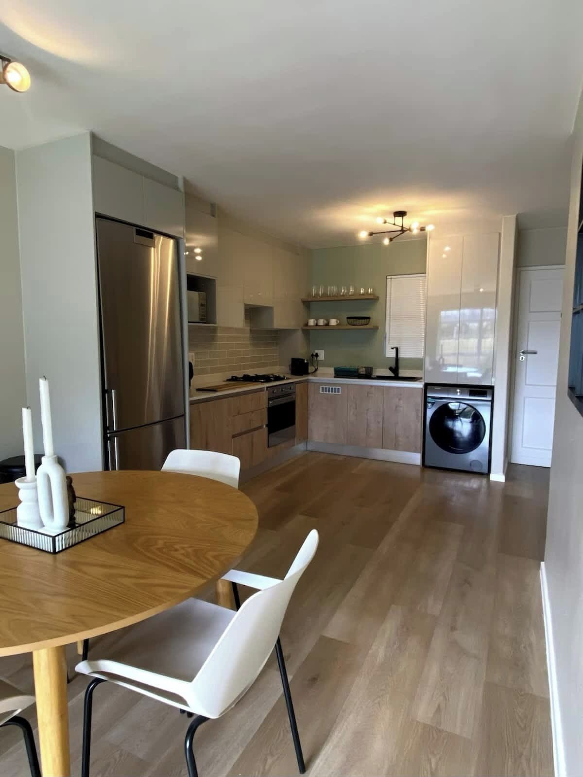 A modern kitchen with a dining area, stainless steel appliances, and a built-in washer and dryer.