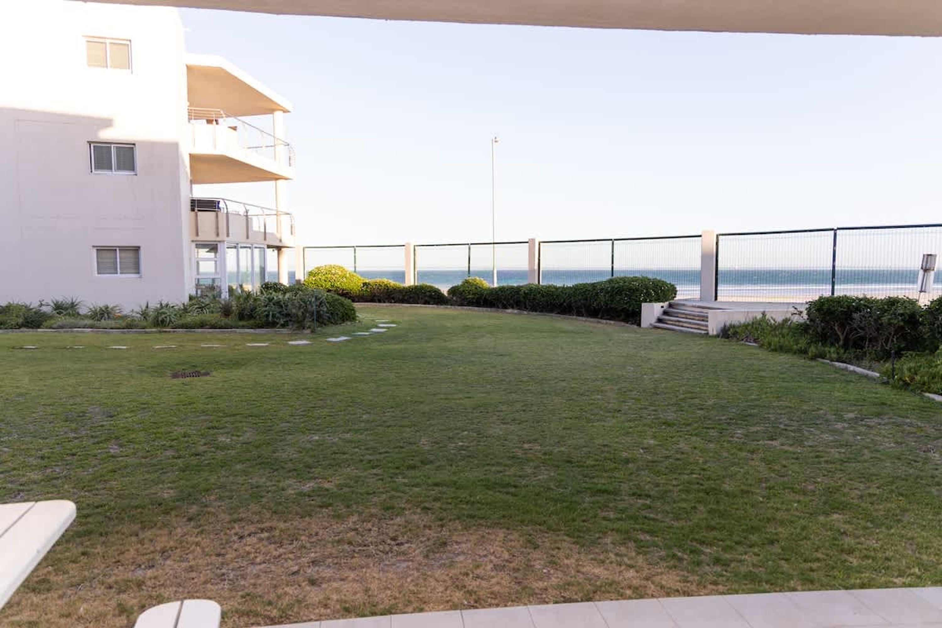 A flat with a view of the sea, a balcony, and a well-maintained lawn.