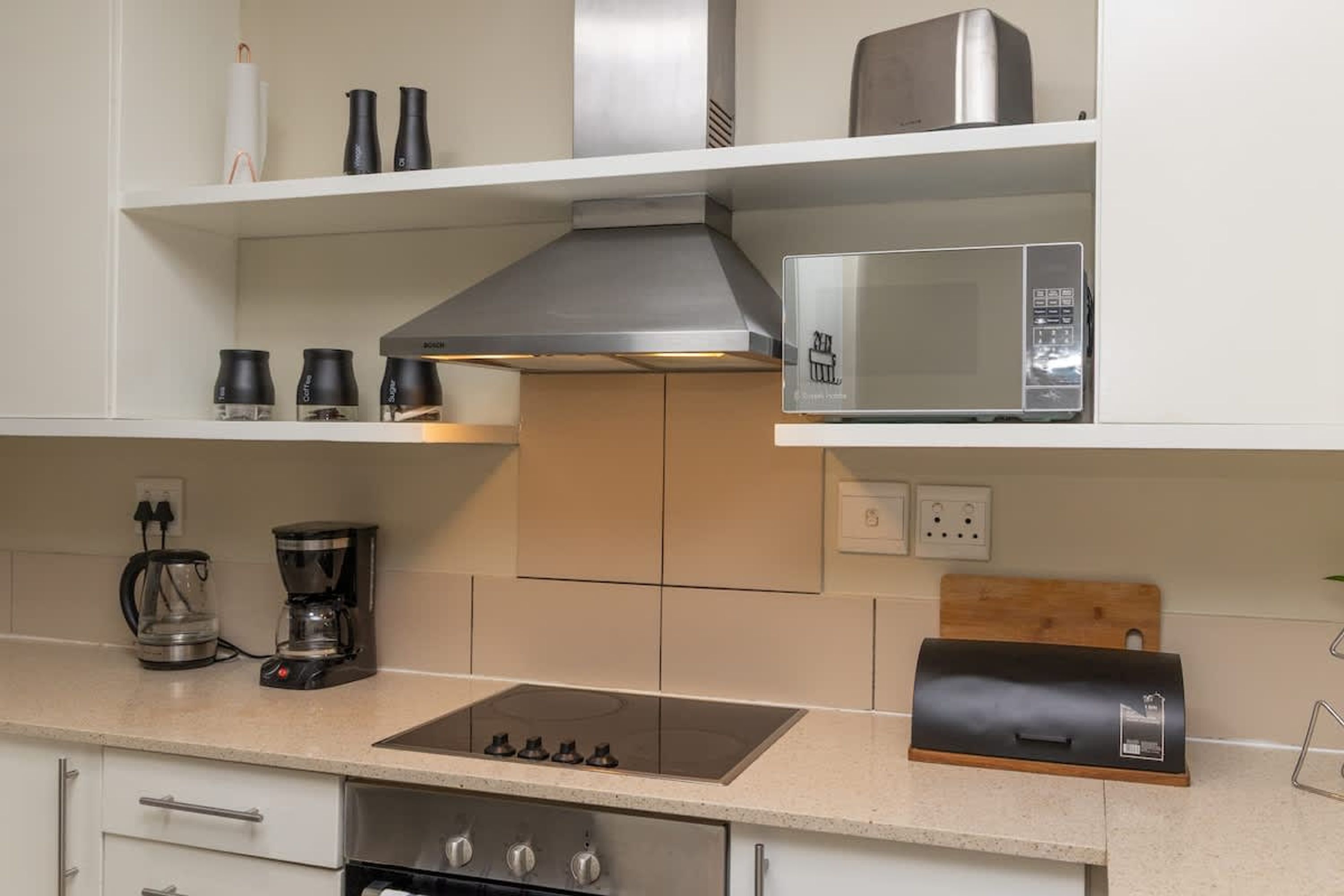 A kitchen with a stove, microwave, coffee maker, and a grill.