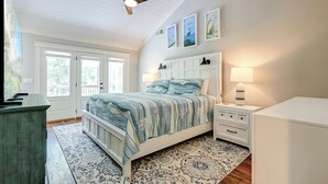 A bedroom with a bed, nightstands, a lamp, a ceiling fan, and artwork on the wall. - Sunset Rentals | 8 Governors Lane (Hilton Head Island)