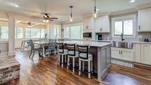 A spacious kitchen with a central island, bar stools, and a dining area with a ceiling fan. - Sunset Rentals | 8 Governors Lane (Hilton Head Island)