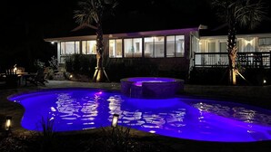 A nighttime view of a house with a swimming pool illuminated by blue lights. - Sunset Rentals | 8 Governors Lane (Hilton Head Island)