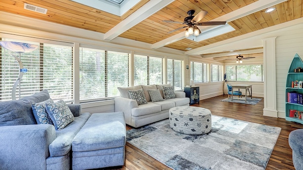 A spacious living room with a high ceiling, large windows, and a cozy seating area. - Sunset Rentals | 8 Governors Lane (Hilton Head Island)