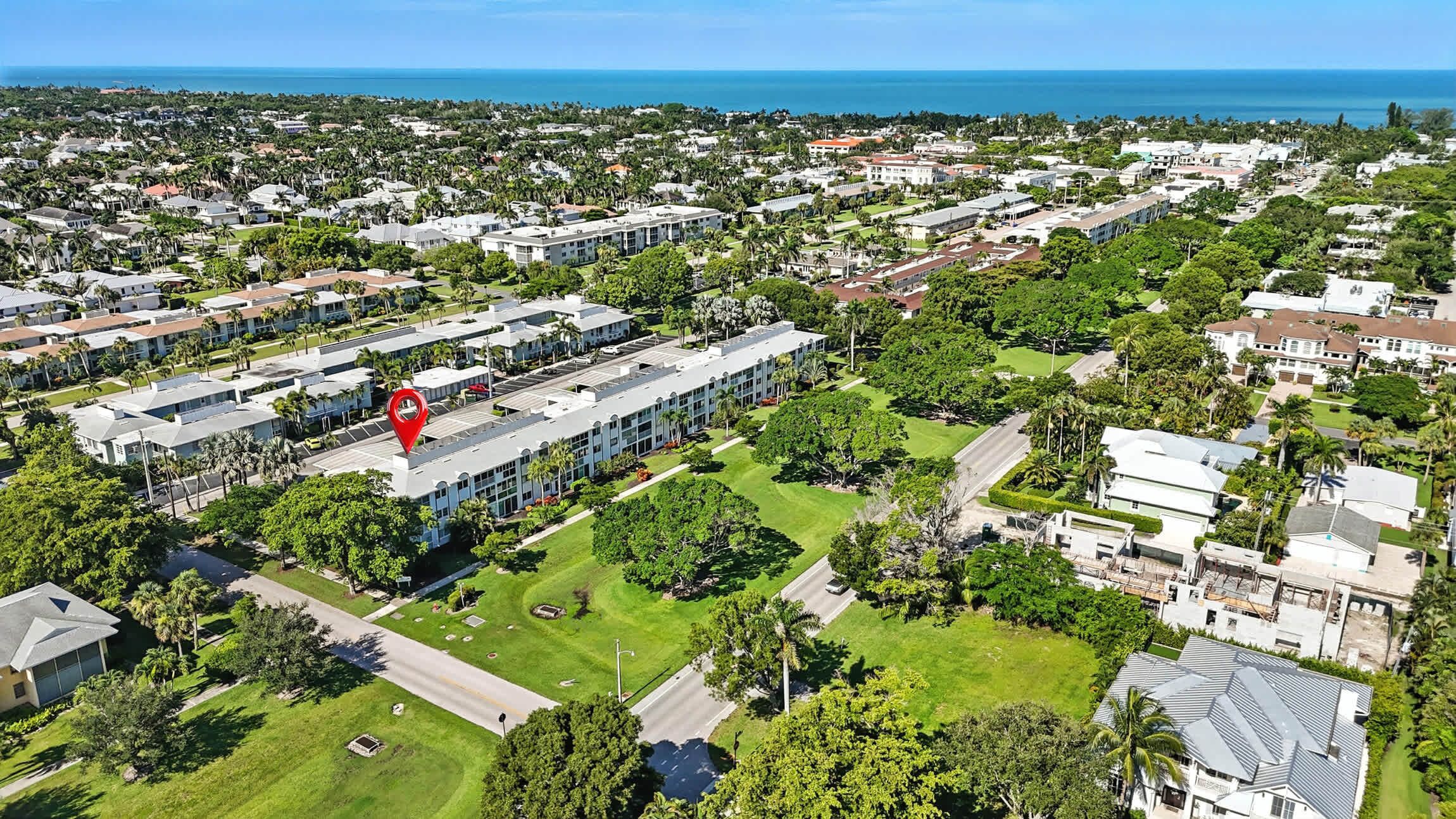An aerial view of a residential area with a large building featuring a prominent red landmark.
