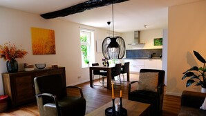 Una sala de estar moderna con una mesa de centro de madera, dos sillones, un sofá y un comedor con una mesa y sillas.