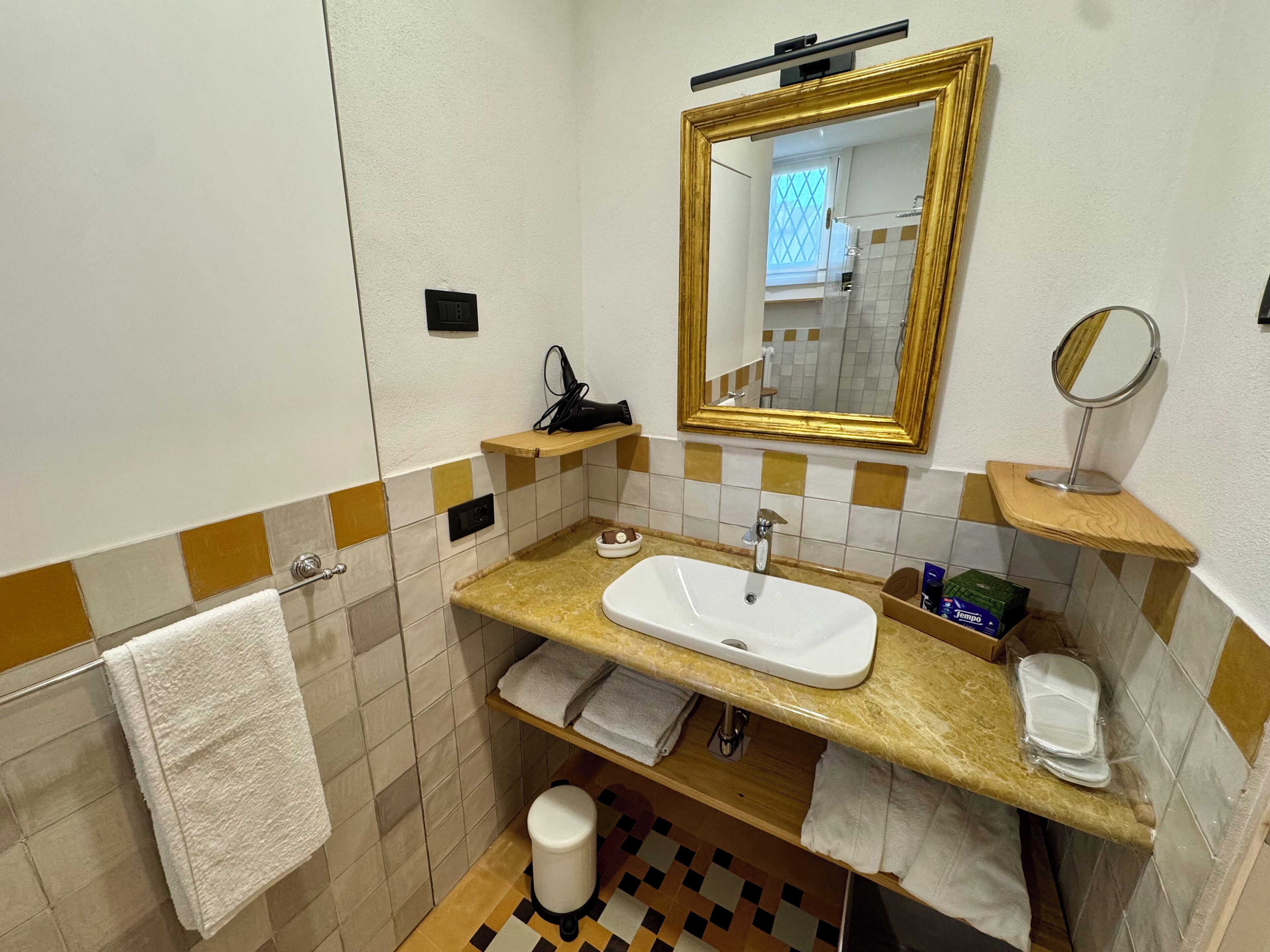 A bathroom with a white sink, a mirror with a gold frame, and a towel rack.