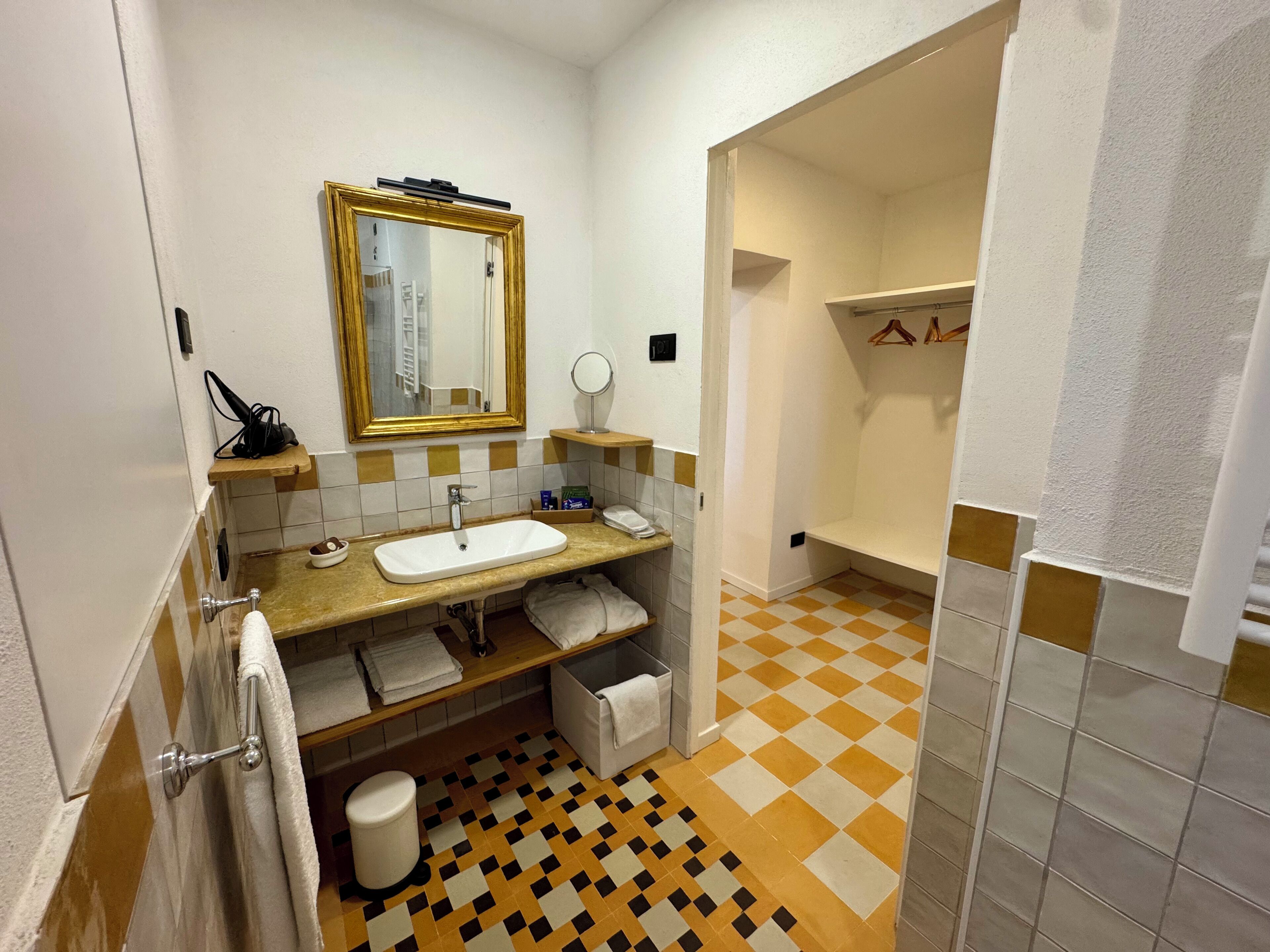 A compact bathroom with a sink, mirror, and towel rack.