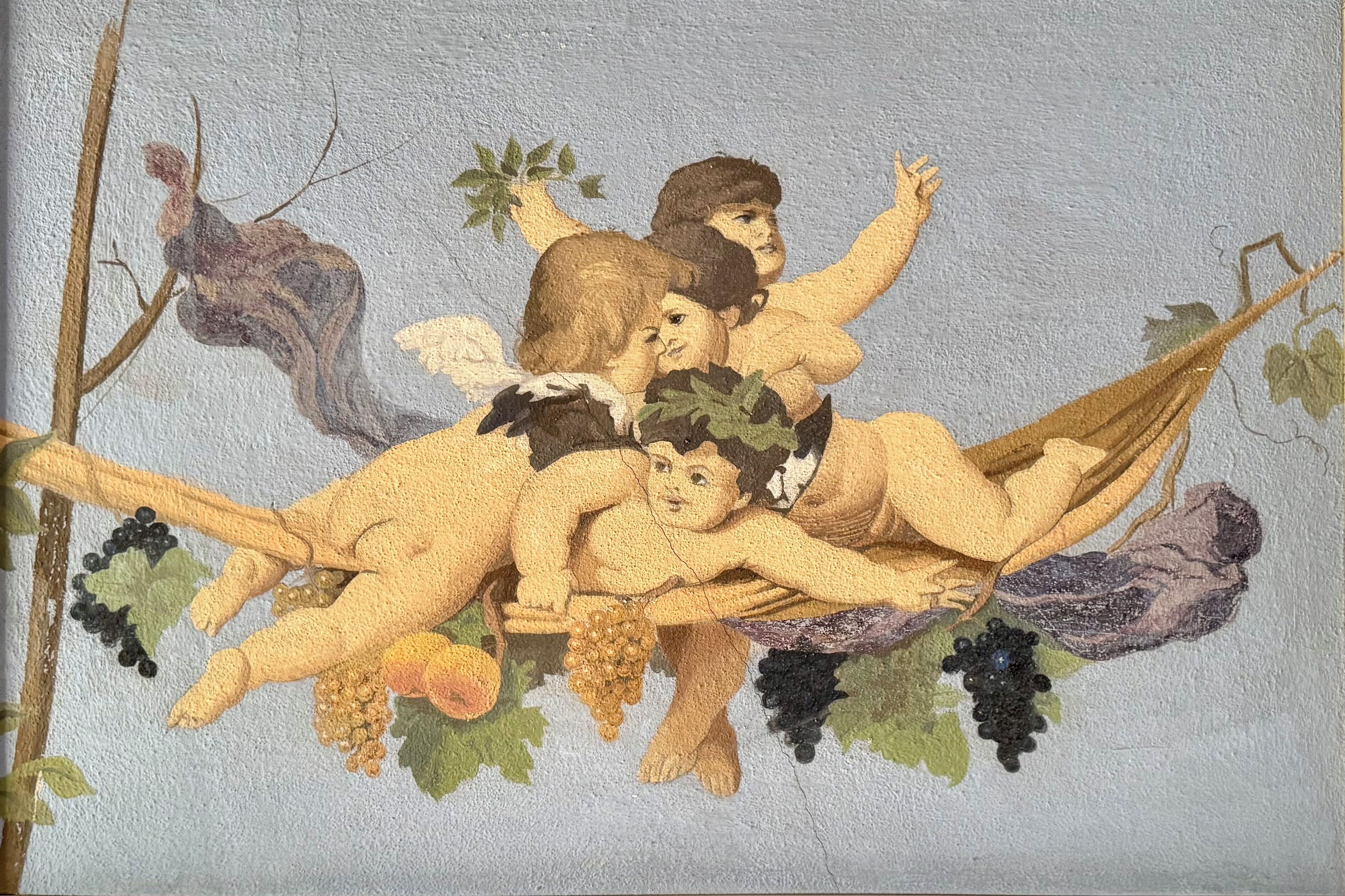 Un mural con querubines y racimos de uvas.